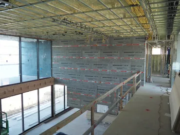 Moisture-resistant board hung on an interior wall beside a glazed façade