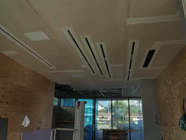 Drywall ceiling with linear diffuser slots above a plywood-lined interior